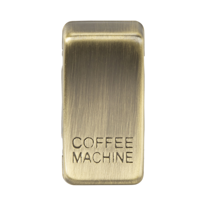 Brass rectangular object with 'COFFEE MACHINE' engraving on a white background